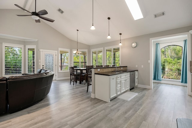 kitchen featuring white cabinetry, sink, a kitchen breakfast bar, hanging light fixtures, and light hardwood / wood-style flooring