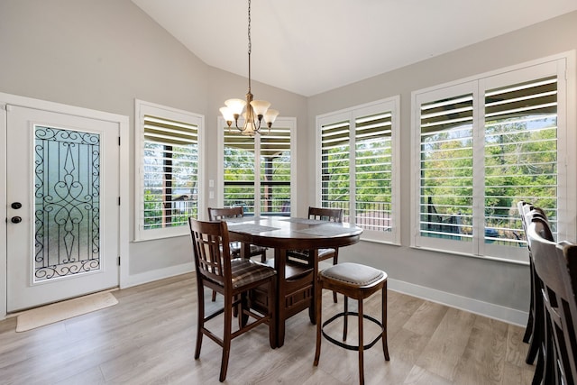 dining room featuring lofted ceiling, plenty of natural light, a chandelier, and light wood-type flooring