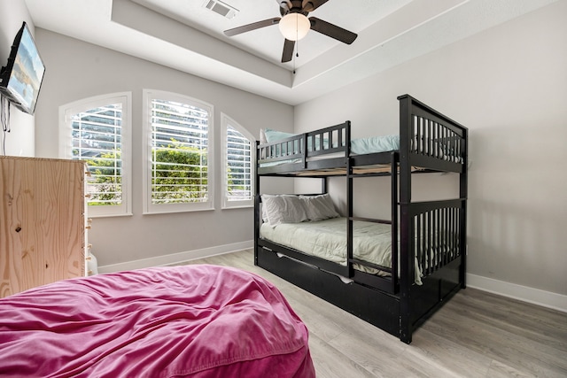 bedroom featuring ceiling fan, a tray ceiling, and hardwood / wood-style floors