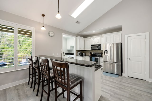 kitchen with pendant lighting, a breakfast bar, white cabinetry, high vaulted ceiling, and stainless steel appliances