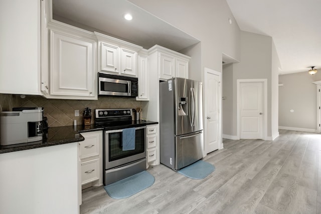 kitchen featuring white cabinetry, light hardwood / wood-style flooring, a towering ceiling, stainless steel appliances, and backsplash