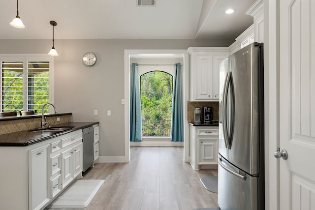 kitchen with pendant lighting, sink, stainless steel appliances, tasteful backsplash, and white cabinets