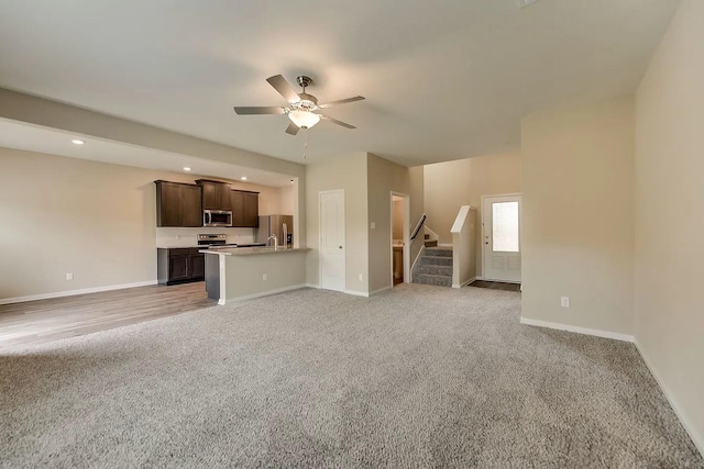 unfurnished living room with light colored carpet and ceiling fan