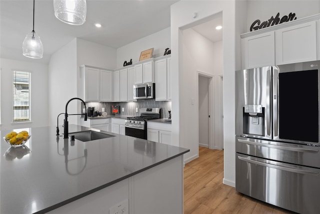 kitchen with appliances with stainless steel finishes, decorative light fixtures, sink, and white cabinets