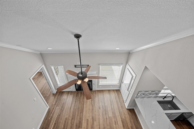 living room featuring crown molding, ceiling fan, a textured ceiling, and light wood-type flooring