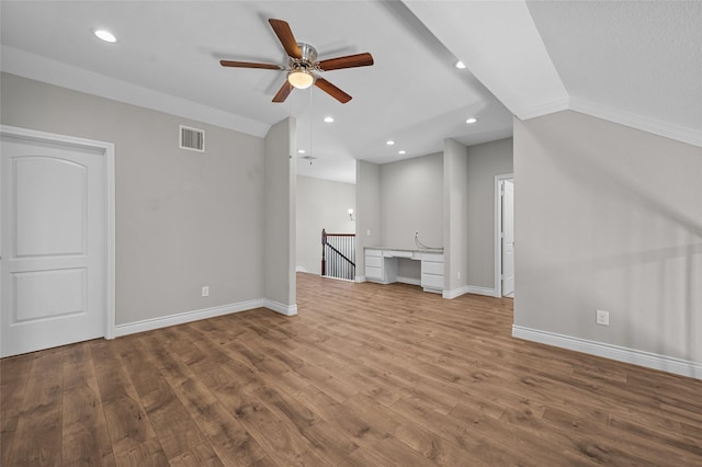 unfurnished living room featuring ceiling fan, wood-type flooring, built in desk, and vaulted ceiling