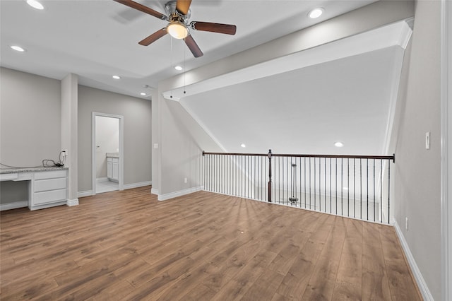 interior space with ceiling fan, wood-type flooring, and built in desk