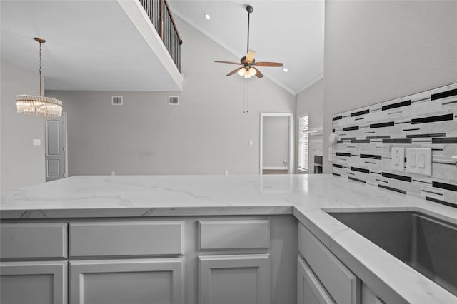 kitchen with high vaulted ceiling, sink, backsplash, ceiling fan, and light stone countertops