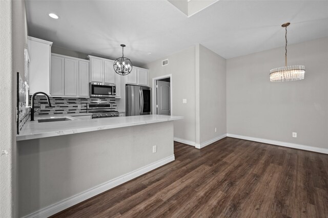 kitchen featuring sink, an inviting chandelier, appliances with stainless steel finishes, kitchen peninsula, and white cabinets