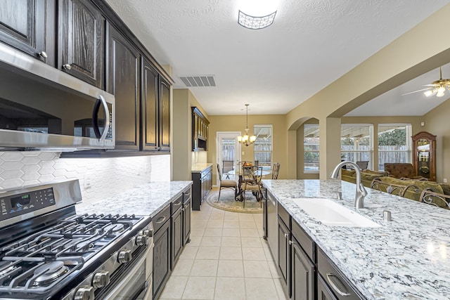 kitchen featuring sink, plenty of natural light, stainless steel appliances, dark brown cabinetry, and light tile patterned flooring