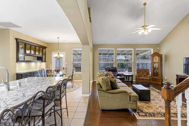 living room featuring hardwood / wood-style floors, vaulted ceiling, a healthy amount of sunlight, and ceiling fan with notable chandelier