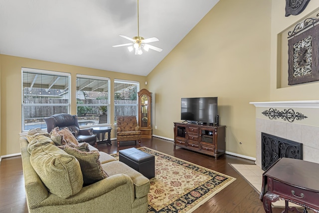 living room with ceiling fan, high vaulted ceiling, a tiled fireplace, and hardwood / wood-style floors