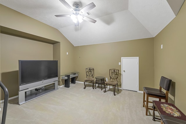 living area with ceiling fan, lofted ceiling, light carpet, and a textured ceiling