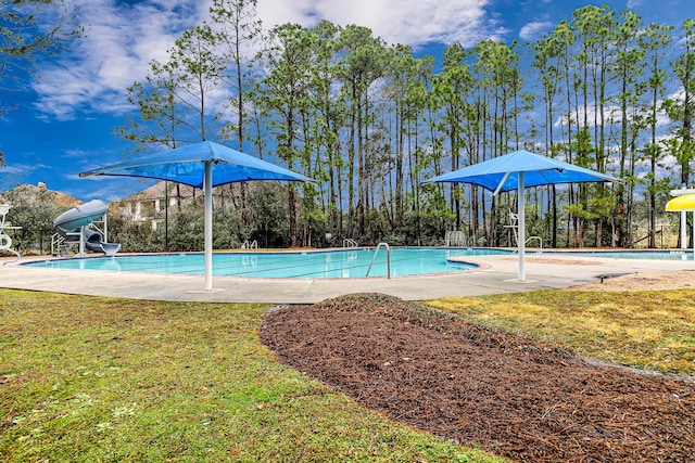 view of swimming pool with a yard and a water slide