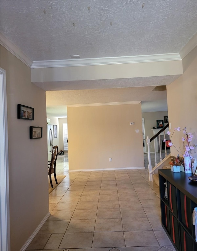 hallway with ornamental molding, light tile patterned floors, and a textured ceiling