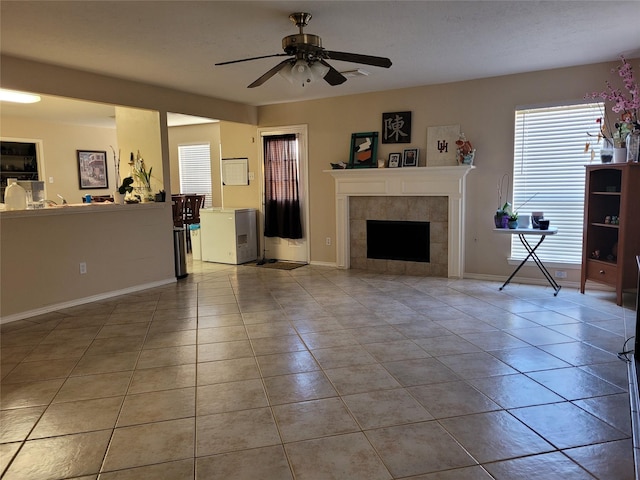 tiled living room with ceiling fan and a tiled fireplace