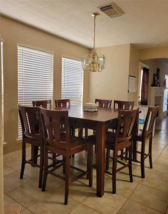 dining space with a chandelier, a textured ceiling, and light tile patterned floors