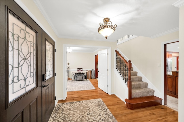 entrance foyer with ornamental molding and light hardwood / wood-style floors