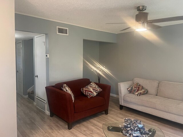 living room with ceiling fan, hardwood / wood-style floors, and a textured ceiling