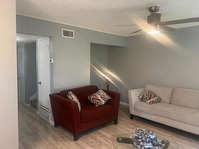 living room featuring hardwood / wood-style floors, crown molding, a textured ceiling, and ceiling fan