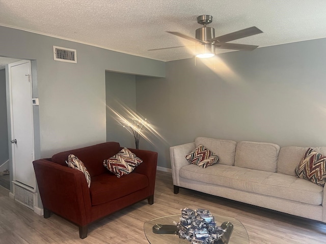 living room featuring ceiling fan, wood-type flooring, and a textured ceiling