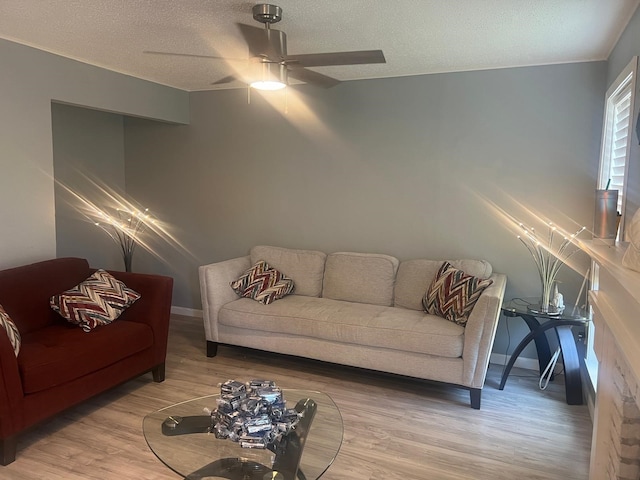 living room with hardwood / wood-style flooring, ceiling fan, and a textured ceiling