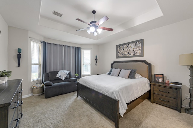 carpeted bedroom with ceiling fan and a raised ceiling