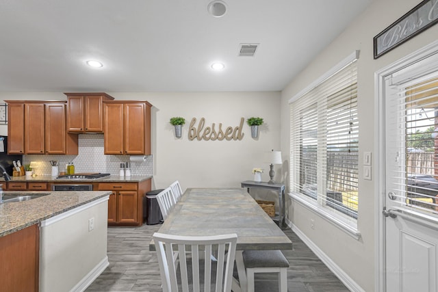 kitchen featuring sink, light stone counters, dark hardwood / wood-style flooring, stainless steel gas stovetop, and backsplash