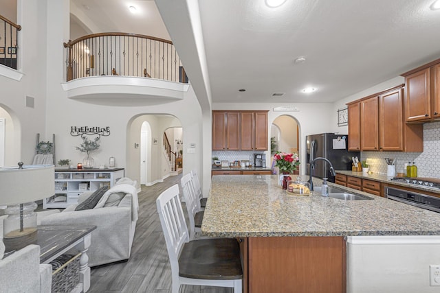 kitchen featuring sink, light stone counters, dark hardwood / wood-style floors, a kitchen island with sink, and decorative backsplash