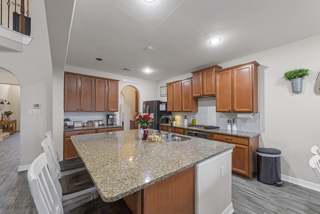 kitchen with sink, appliances with stainless steel finishes, a kitchen bar, a center island with sink, and light wood-type flooring