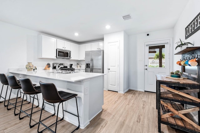 kitchen with white cabinetry, sink, kitchen peninsula, and appliances with stainless steel finishes