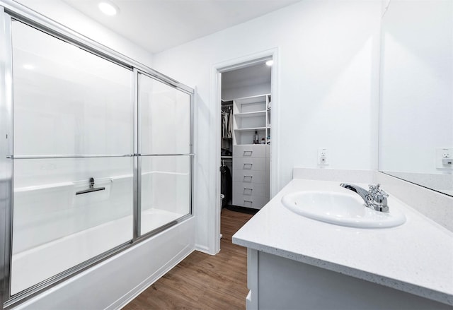 bathroom with wood-type flooring, combined bath / shower with glass door, and vanity