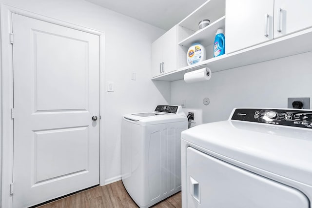 washroom featuring hardwood / wood-style floors, cabinets, and washing machine and clothes dryer