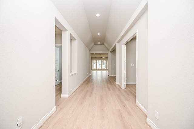 hallway with lofted ceiling and light wood-type flooring