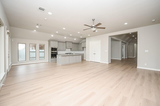 unfurnished living room featuring lofted ceiling, sink, ceiling fan, and light hardwood / wood-style flooring