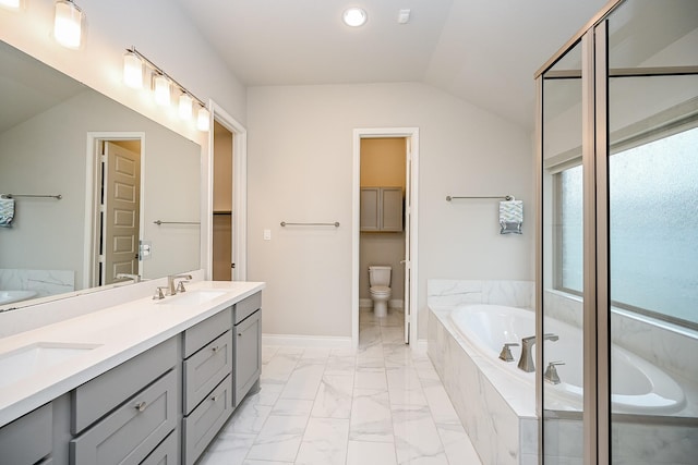 bathroom featuring a relaxing tiled tub, vanity, toilet, and vaulted ceiling