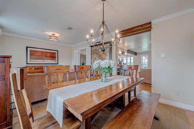 dining area with a notable chandelier, ornamental molding, and light wood-type flooring