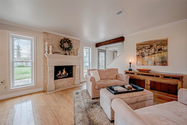 living room featuring a high end fireplace, light hardwood / wood-style flooring, and ornamental molding