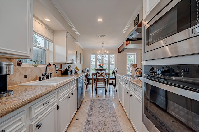 kitchen with decorative light fixtures, sink, white cabinets, backsplash, and stainless steel appliances