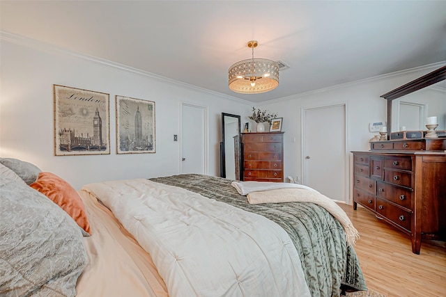 bedroom featuring crown molding, a chandelier, and light wood-type flooring