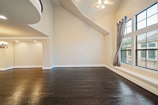 empty room featuring crown molding, a towering ceiling, ceiling fan with notable chandelier, and dark wood-type flooring