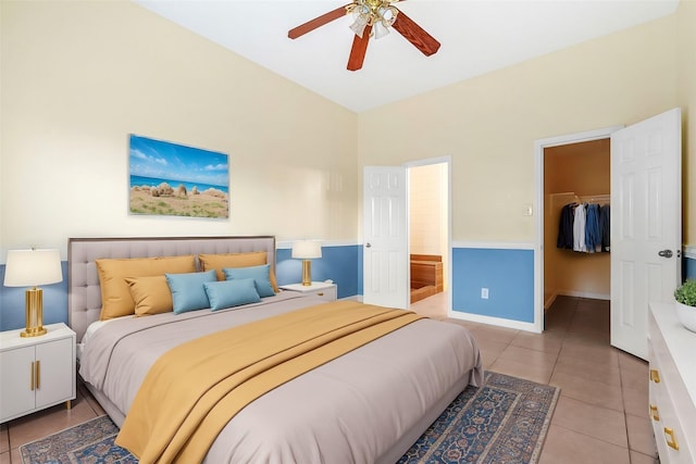 bedroom with light tile patterned floors, ensuite bath, ceiling fan, a walk in closet, and a closet