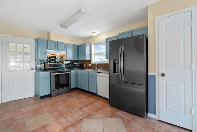 kitchen featuring appliances with stainless steel finishes, tasteful backsplash, sink, light tile patterned floors, and blue cabinetry