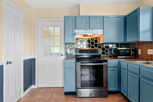 kitchen with blue cabinetry, stainless steel appliances, and light tile patterned flooring