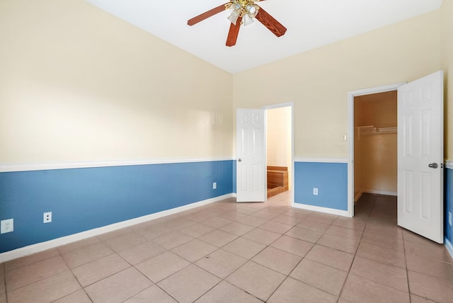 unfurnished bedroom featuring a spacious closet, light tile patterned floors, ceiling fan, and a closet