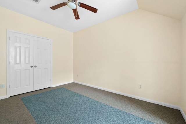 unfurnished bedroom with dark colored carpet, lofted ceiling, ceiling fan, and a closet