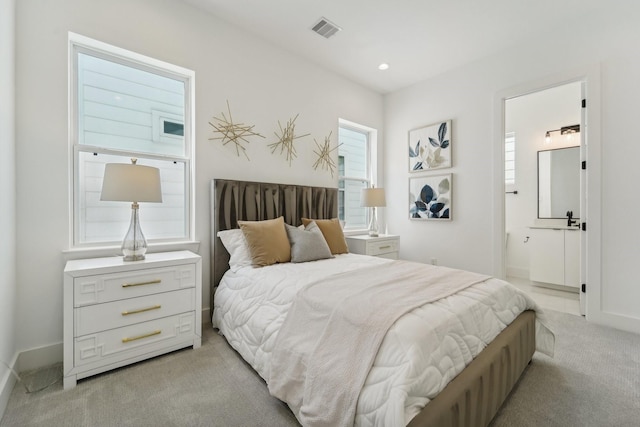 bedroom with light colored carpet and connected bathroom