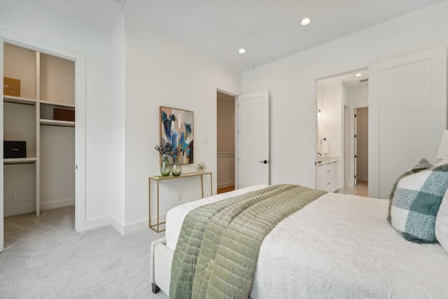 carpeted bedroom with a walk in closet, ensuite bathroom, and a closet