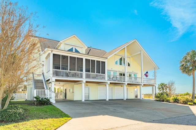 raised beach house featuring a garage and a sunroom