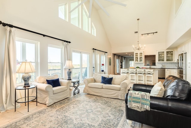 living room with light tile patterned floors, a notable chandelier, and high vaulted ceiling